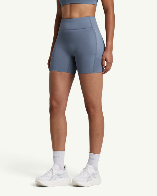 Amateur women's blue high-waist compression shorts with side pockets and grip hem, worn by a runner.