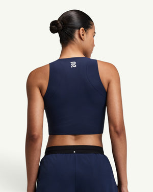 Amateur women's navy blue Adapto compression race crop top with back logo, viewed from behind on a model.