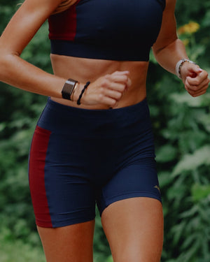 Amateur women's navy and maroon textured knit 5-inch short tights with a wide waistband worn by a runner outdoors