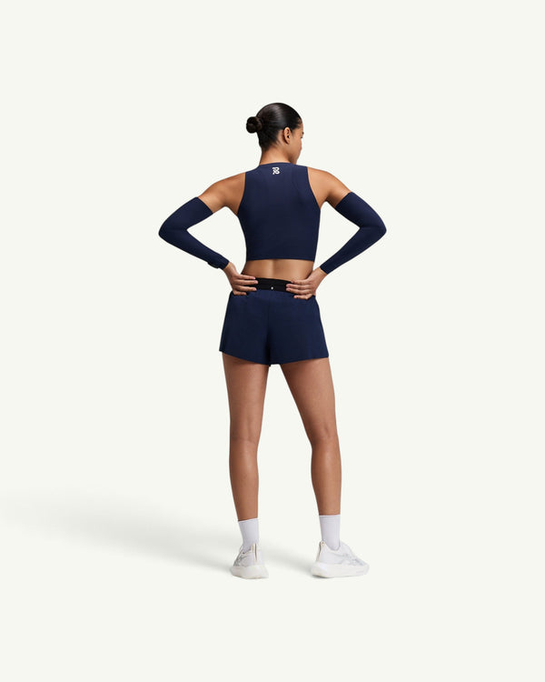 Amateur women's navy Adapto 2-way zip race crop top with matching shorts and arm sleeves, back view