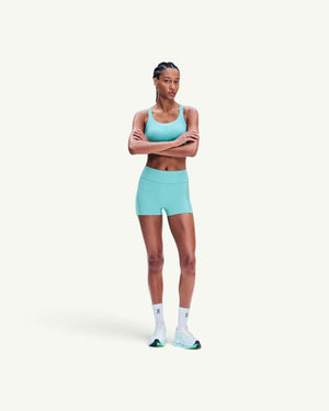 Amateur women's 3-inch performance tights in light turquoise, worn by a model with a matching sports bra.