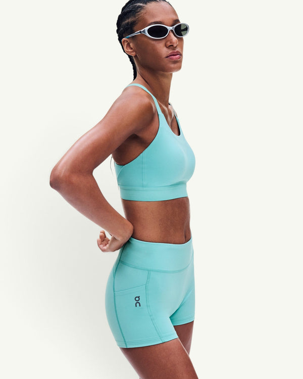 Amateur women's 3-inch performance tights in light turquoise, worn by a model with a matching sports bra.