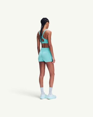 Amateur women's 3-inch performance tights in bright turquoise, worn by a model from the back view.