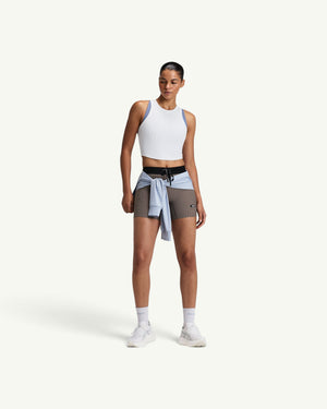 Amateur women's white ribbed performance tank top worn by a model with athletic shorts and a light blue sweater